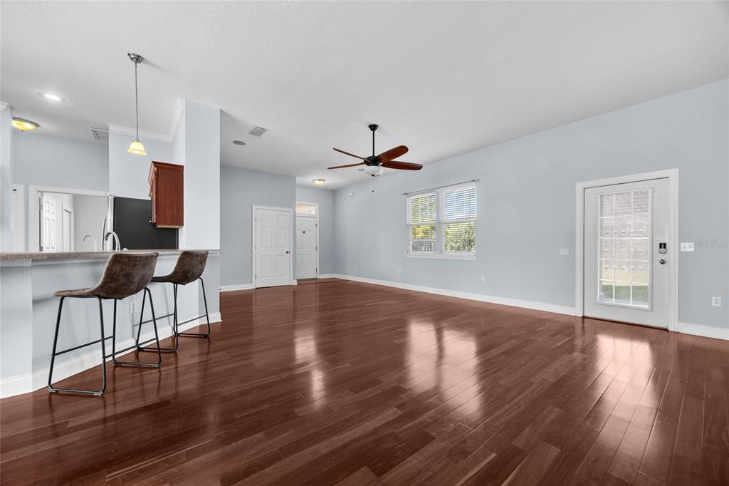 A living area with hardwood floors, a ceiling fan, and a kitchen breakfast bar — 16609 NW 166TH DRIVE, ALACHUA, FL