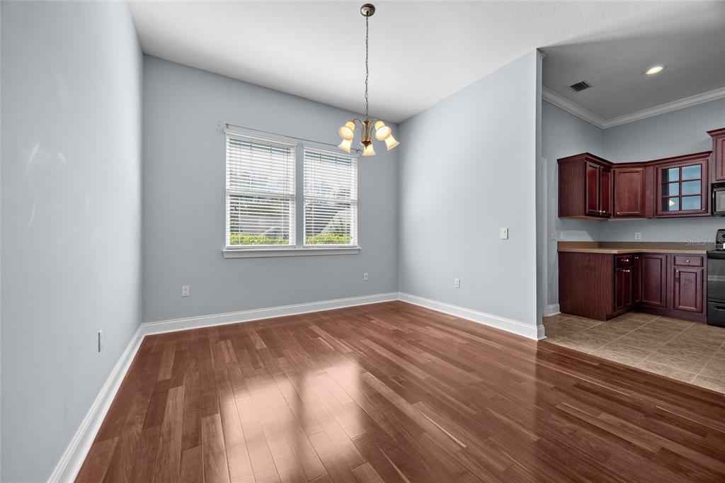 A dining area with light blue walls, hardwood flooring, a chandelier, and an adjacent kitchen — 16609 NW 166TH DRIVE, ALACHUA, FL