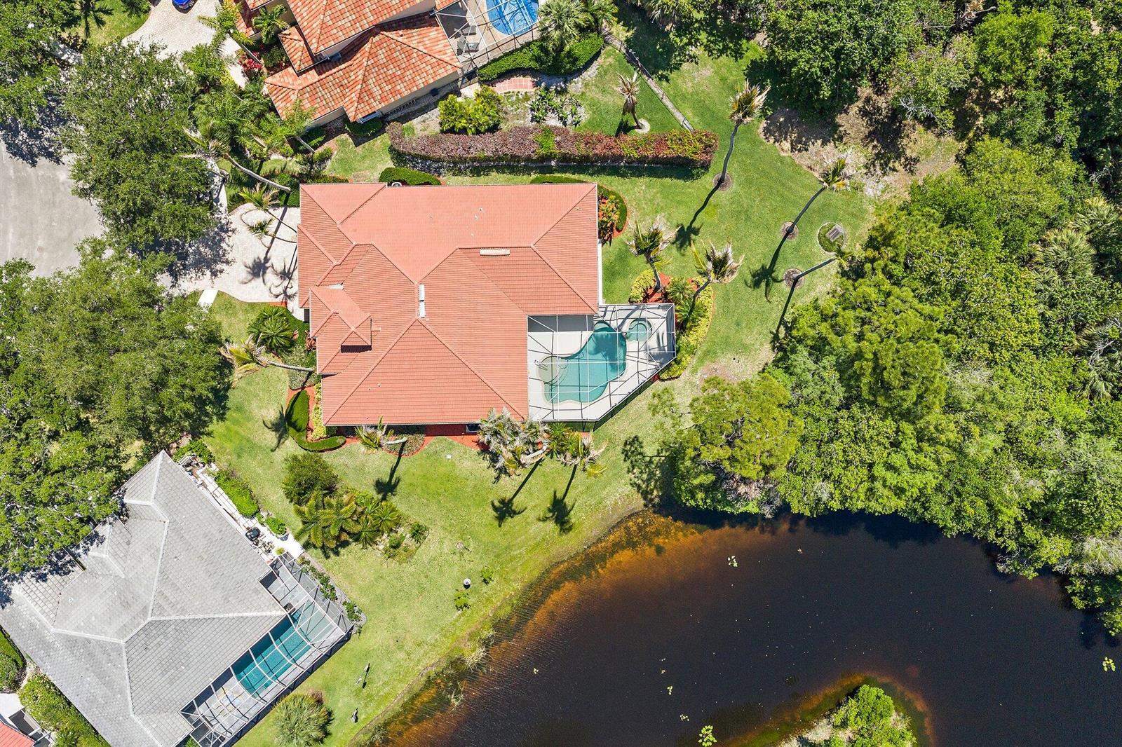 An aerial view shows a house with a red tile roof, pool, and backyard pond — 19189 Tamara Lane, Jupiter FL 33458, JUPITER, FL