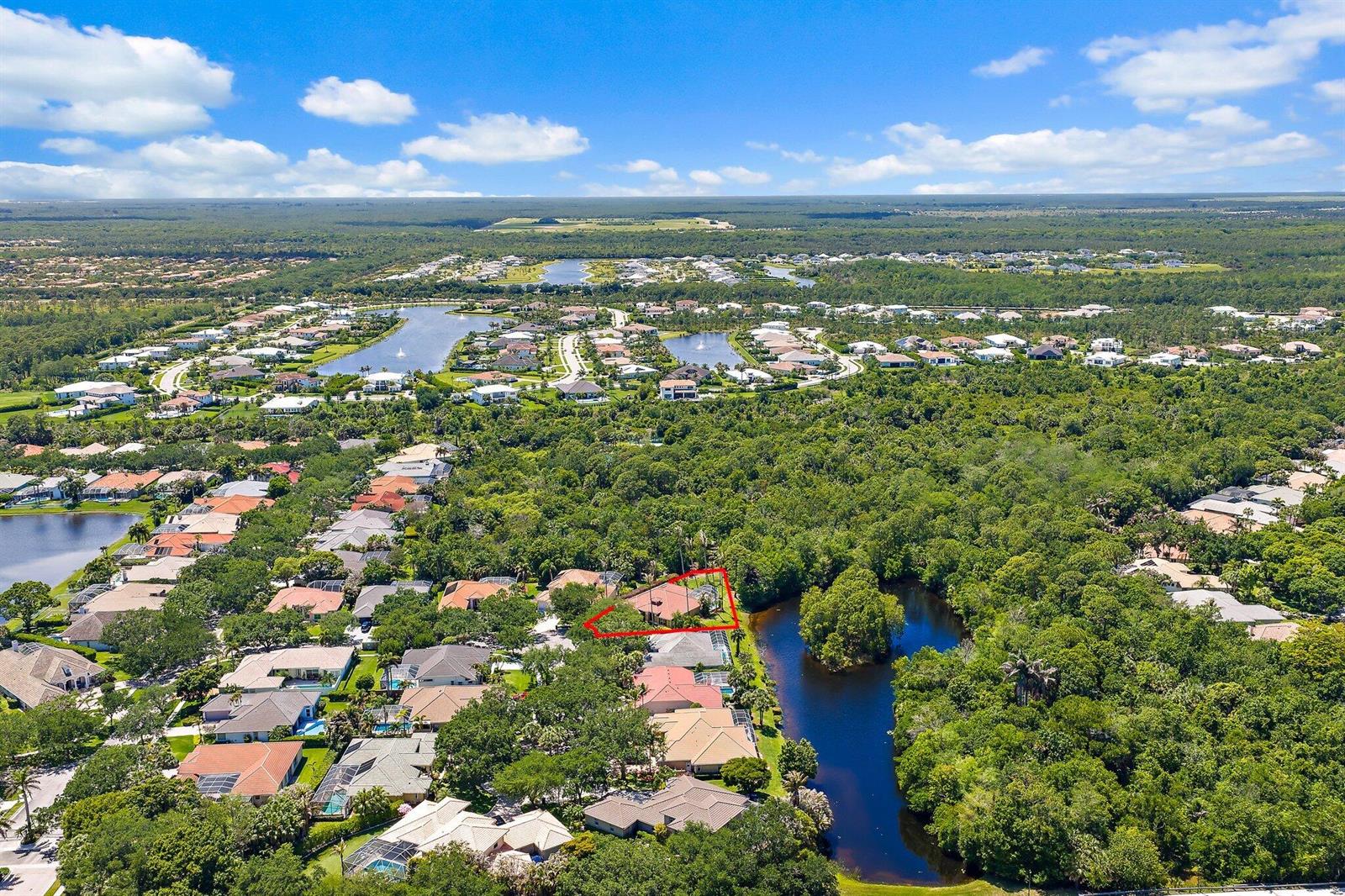 An aerial view shows a residential house outlined in red, situated near a wooded pond — 19189 Tamara Lane, Jupiter FL 33458, JUPITER, FL