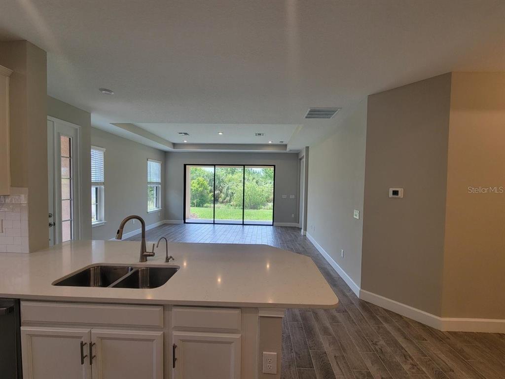 A kitchen island with a double sink overlooks an open living area with sliding glass doors — 5331 RUSHMERE COURT, PALMETTO, FL