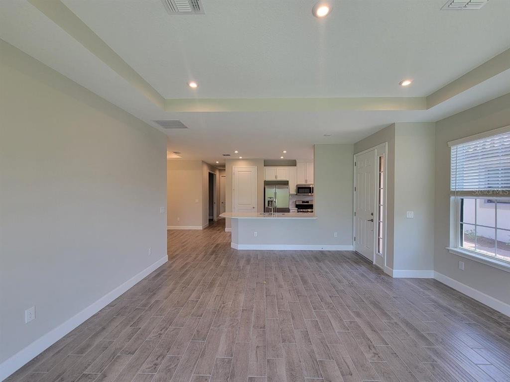 An open-concept living area features wood-look tile flooring, a tray ceiling, and a kitchen island — 5331 RUSHMERE COURT, PALMETTO, FL