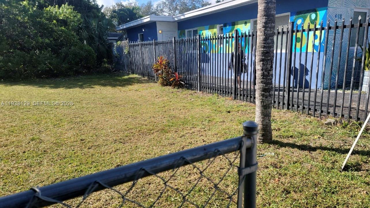 A fenced yard sits in front of a blue building with a colorful mural — 120 NE 56th St, Miami FL 33137, MIAMI, FL