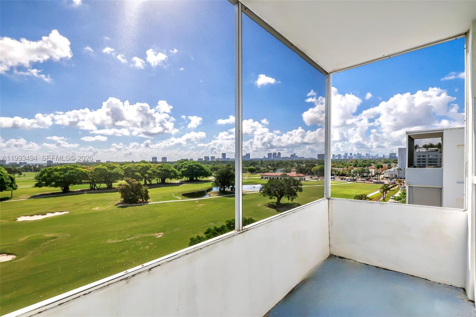 A balcony with a screen enclosure overlooks a golf course and a distant city skyline — 1700 Pierce St # 804, Hollywood FL 33020, HOLLYWOOD, FL