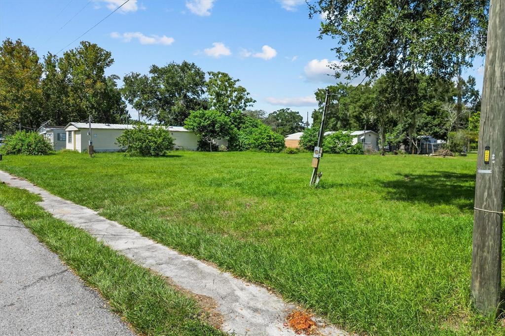 A grassy vacant lot sits next to a sidewalk with a utility pole in the foreground — 636 3RD STREET, POLK CITY, FL