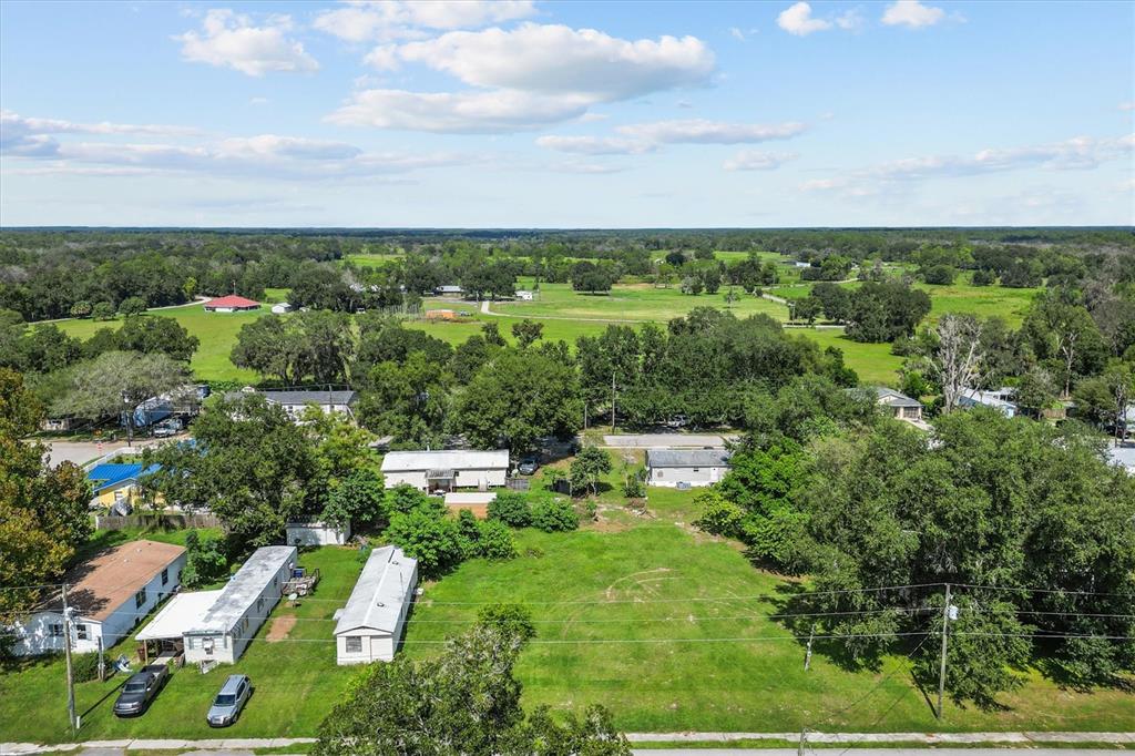 An aerial view shows several mobile homes situated on a grassy lot with scattered trees — 636 3RD STREET, POLK CITY, FL