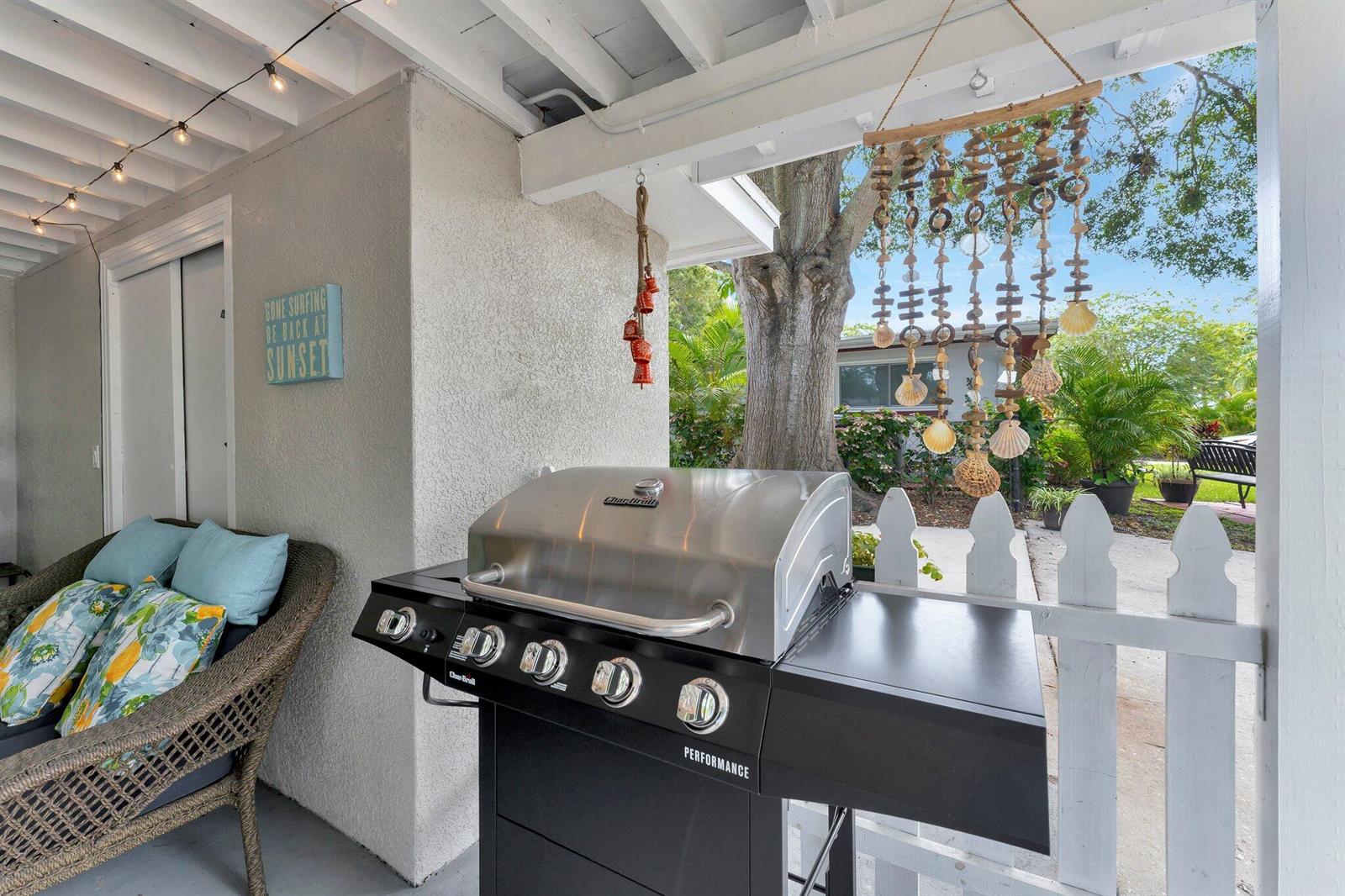 A covered patio features a stainless steel grill, wicker seating, and hanging shell decor — 1555 Shirley Place, Largo FL 33770, LARGO, FL