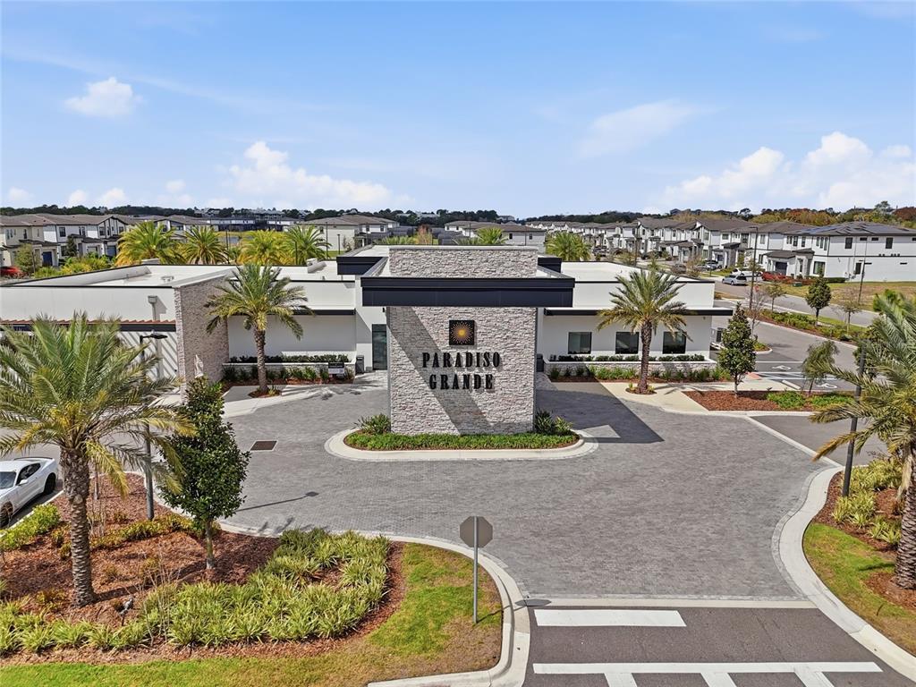 An aerial view shows the stone-faced entrance sign for Paradiso Grande with surrounding palm trees — 10556 EBB TIDE LANE, ORLANDO, FL