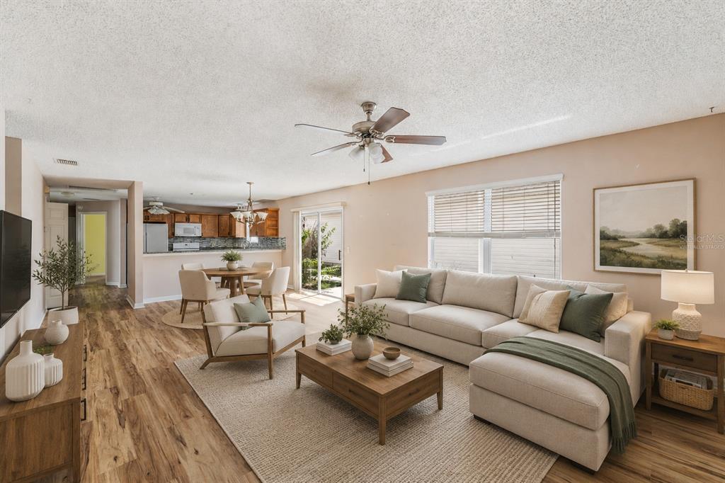 A living room with wood-look flooring, a sectional sofa, and an adjacent dining area — 8932 SE 168TH SEDGWICK PLACE, THE VILLAGES, FL