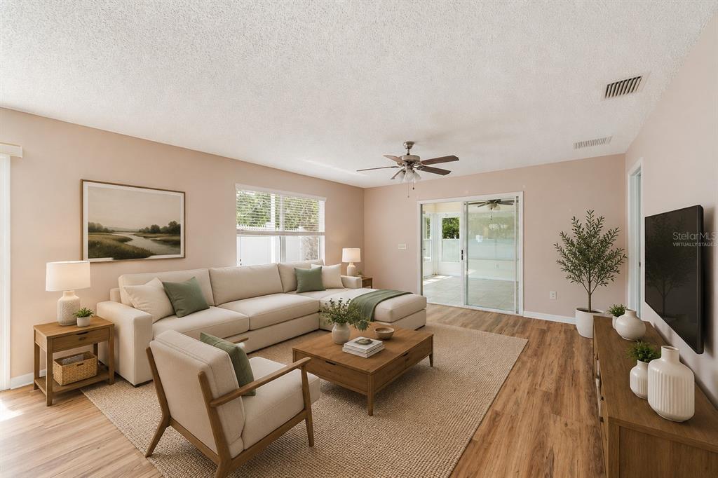 A living room features a sectional sofa, a coffee table, and wood-look flooring — 8932 SE 168TH SEDGWICK PLACE, THE VILLAGES, FL