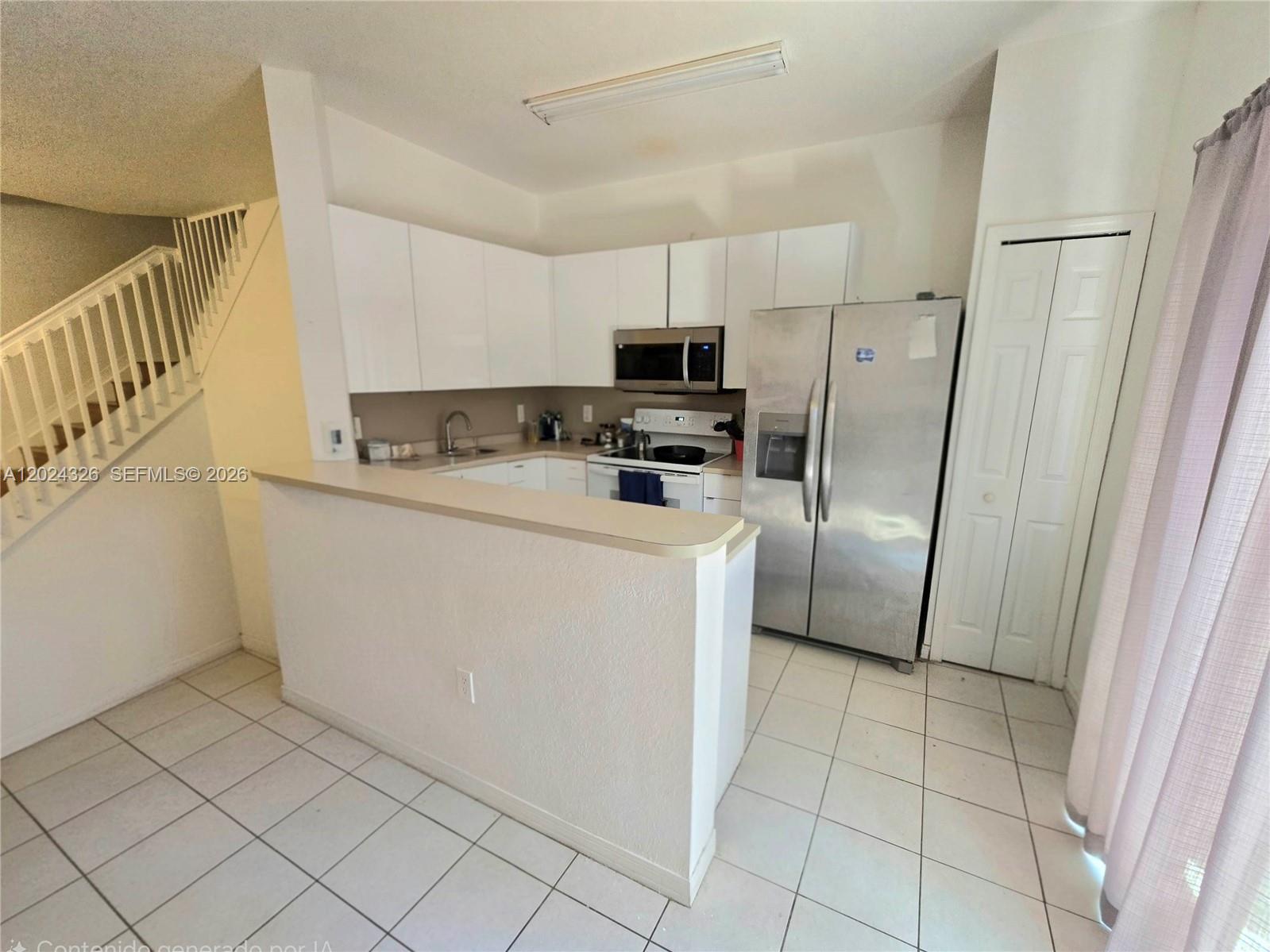 A kitchen features white cabinets, stainless steel appliances, a breakfast bar, and tiled flooring — 10778 NW 84th St # 27, Doral FL 33178, DORAL, FL
