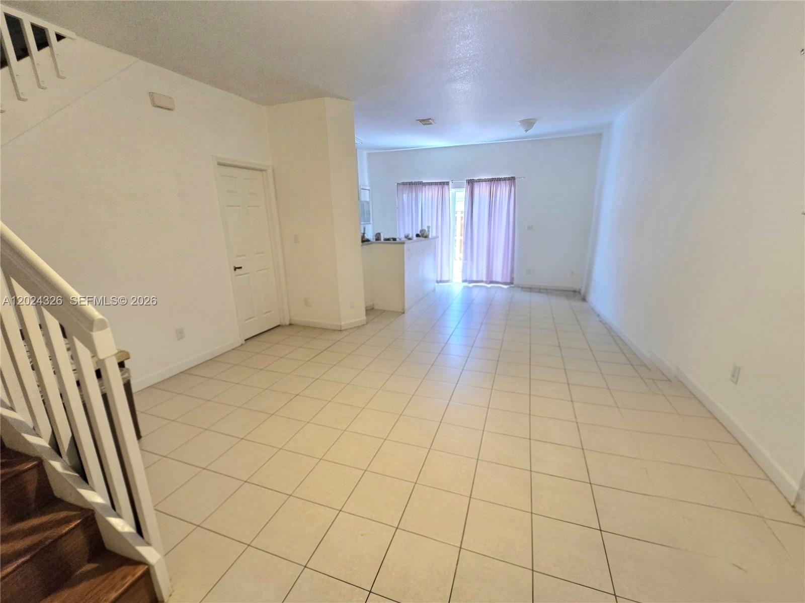 An open-concept living area features white walls, tile flooring, and a staircase on the left — 10778 NW 84th St # 27, Doral FL 33178, DORAL, FL