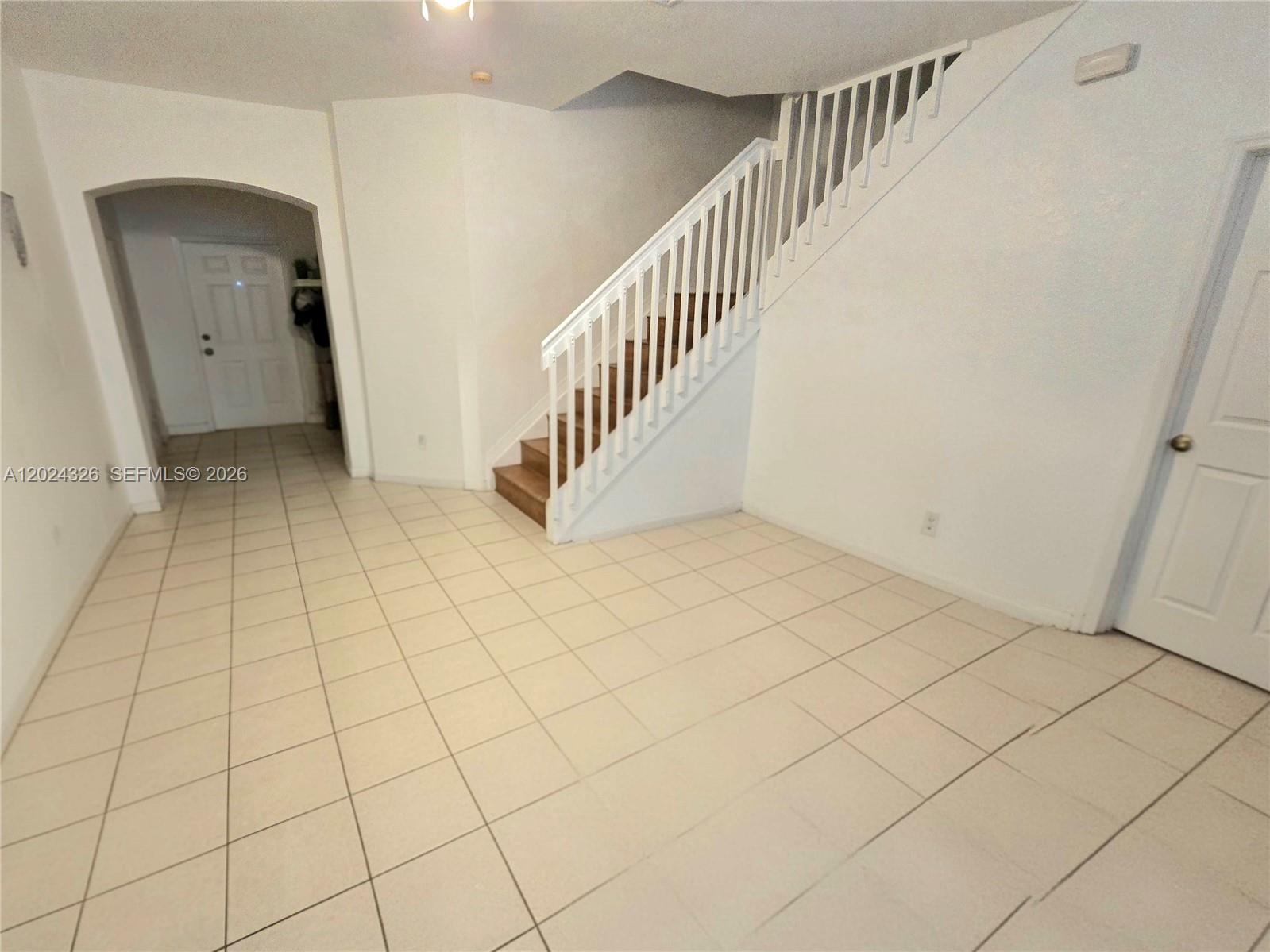 An interior view shows a tiled floor, a staircase with white railings, and two doorways — 10778 NW 84th St # 27, Doral FL 33178, DORAL, FL