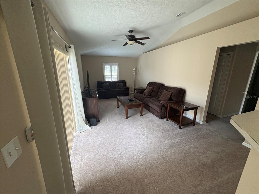 A living room with beige walls, brown carpet, and two brown sofas — 3942 WARBLER DRIVE, WINTER HAVEN, FL