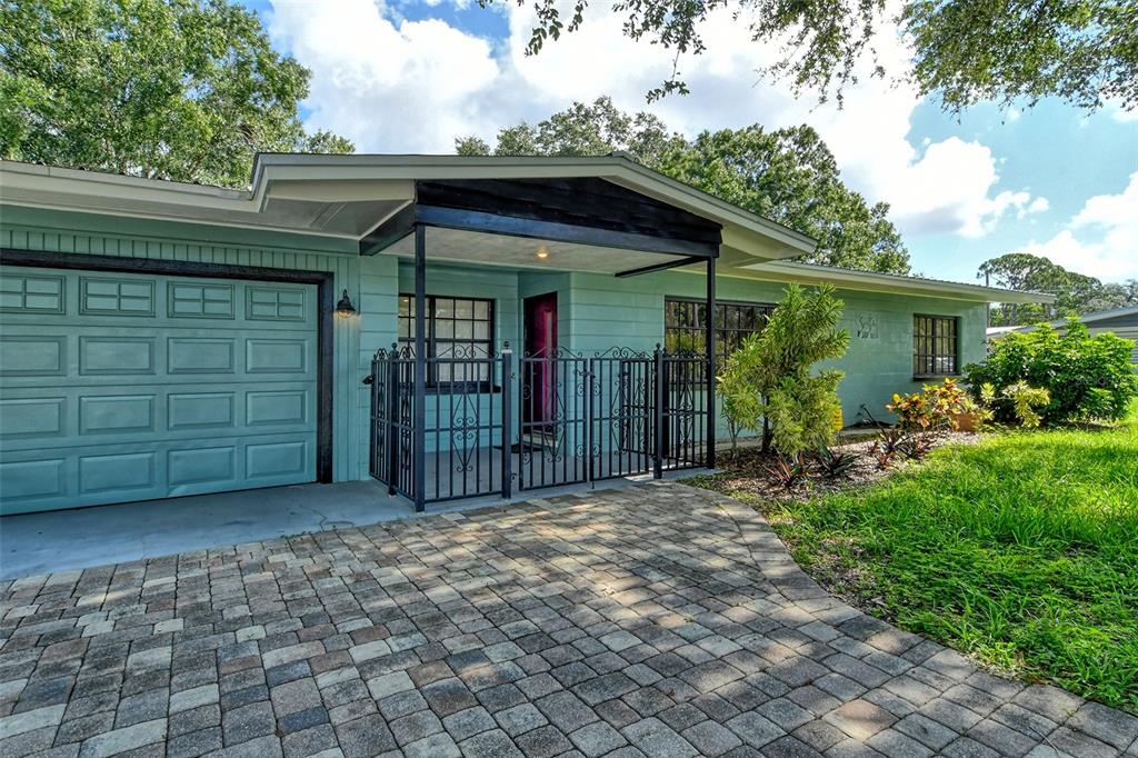 A light green house with a paved driveway, a garage, and a gated front porch — 2309 LYNN STREET, SARASOTA, FL