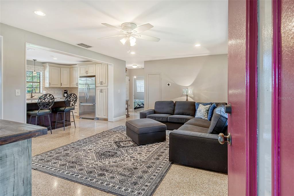 An open-concept living room and kitchen feature a sectional sofa, area rug, and stainless appliances — 2309 LYNN STREET, SARASOTA, FL