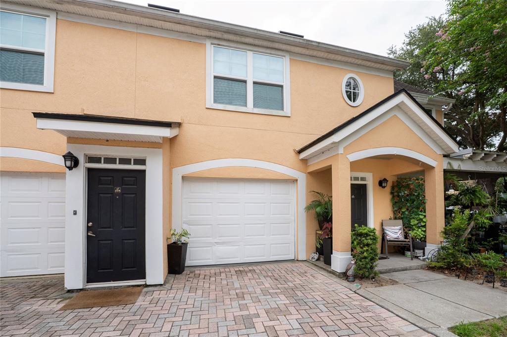 The exterior of a two-story peach-colored townhouse features a garage, a front door, and landscaping — 3432 WESTCHESTER SQUARE BOULEVARD UNIT 203, ORLANDO, FL