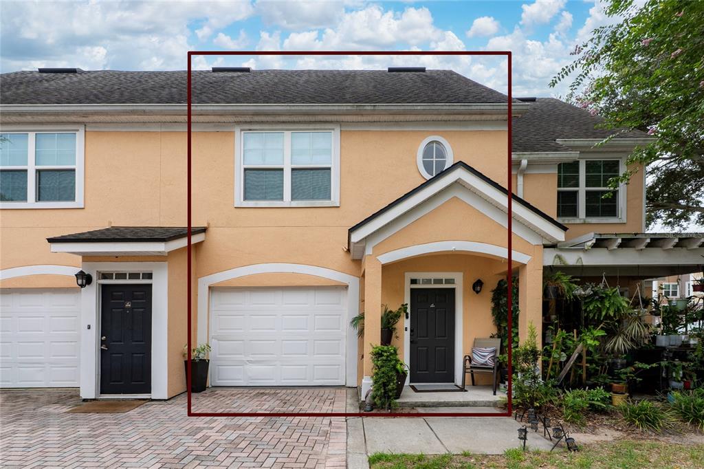 Exterior view of a two-story peach-colored townhouse with a garage and a front entrance — 3432 WESTCHESTER SQUARE BOULEVARD UNIT 203, ORLANDO, FL