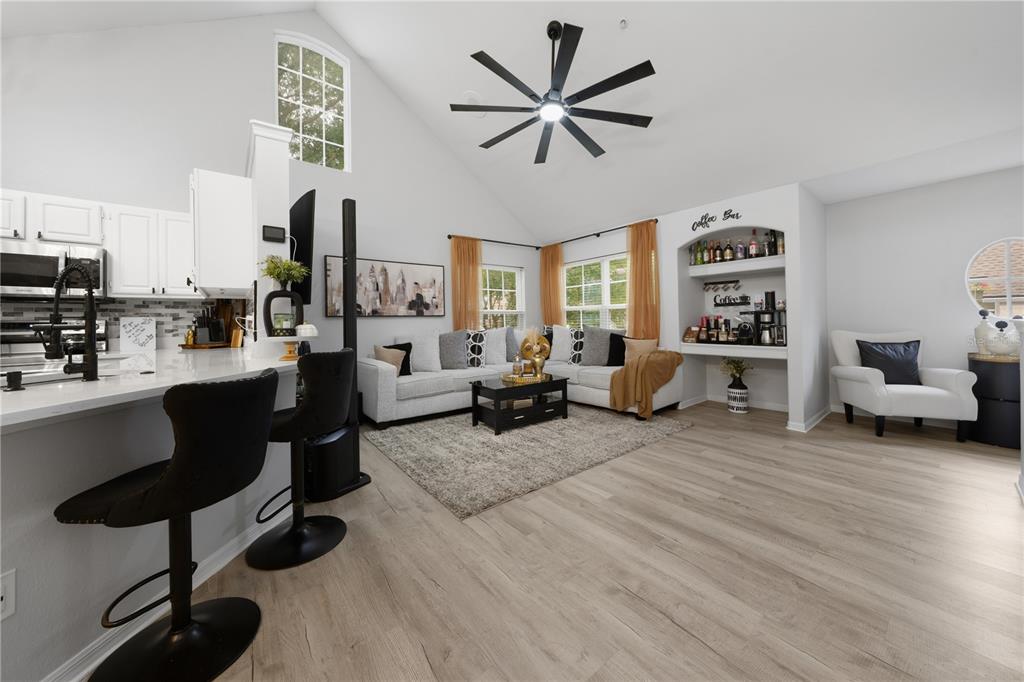 A bright living room features a vaulted ceiling, light wood flooring, and an integrated coffee bar — 3432 WESTCHESTER SQUARE BOULEVARD UNIT 203, ORLANDO, FL