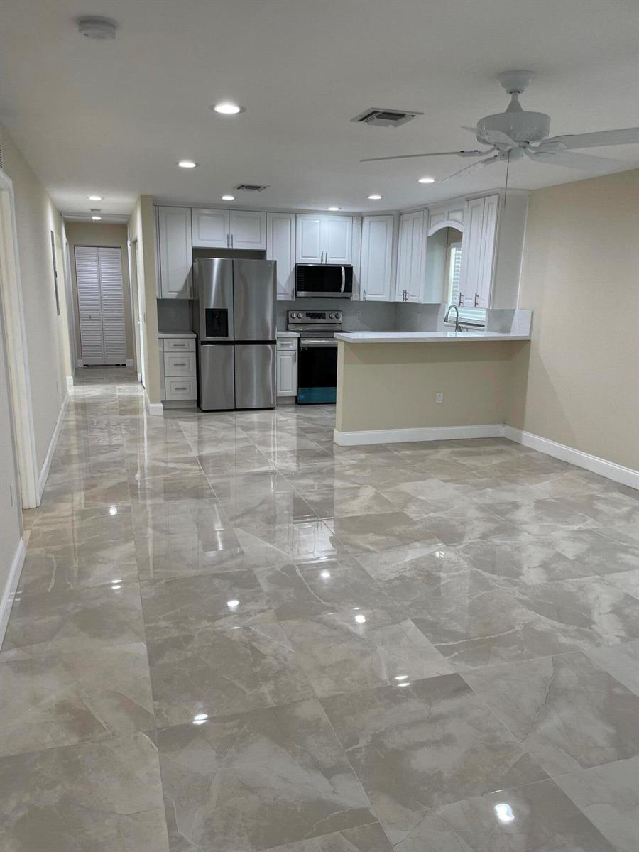 A kitchen with white cabinets, stainless steel appliances, and large, glossy, light-colored floor tiles — 962 29th Street, West Palm Beach FL 33407, WEST PALM BEACH, FL