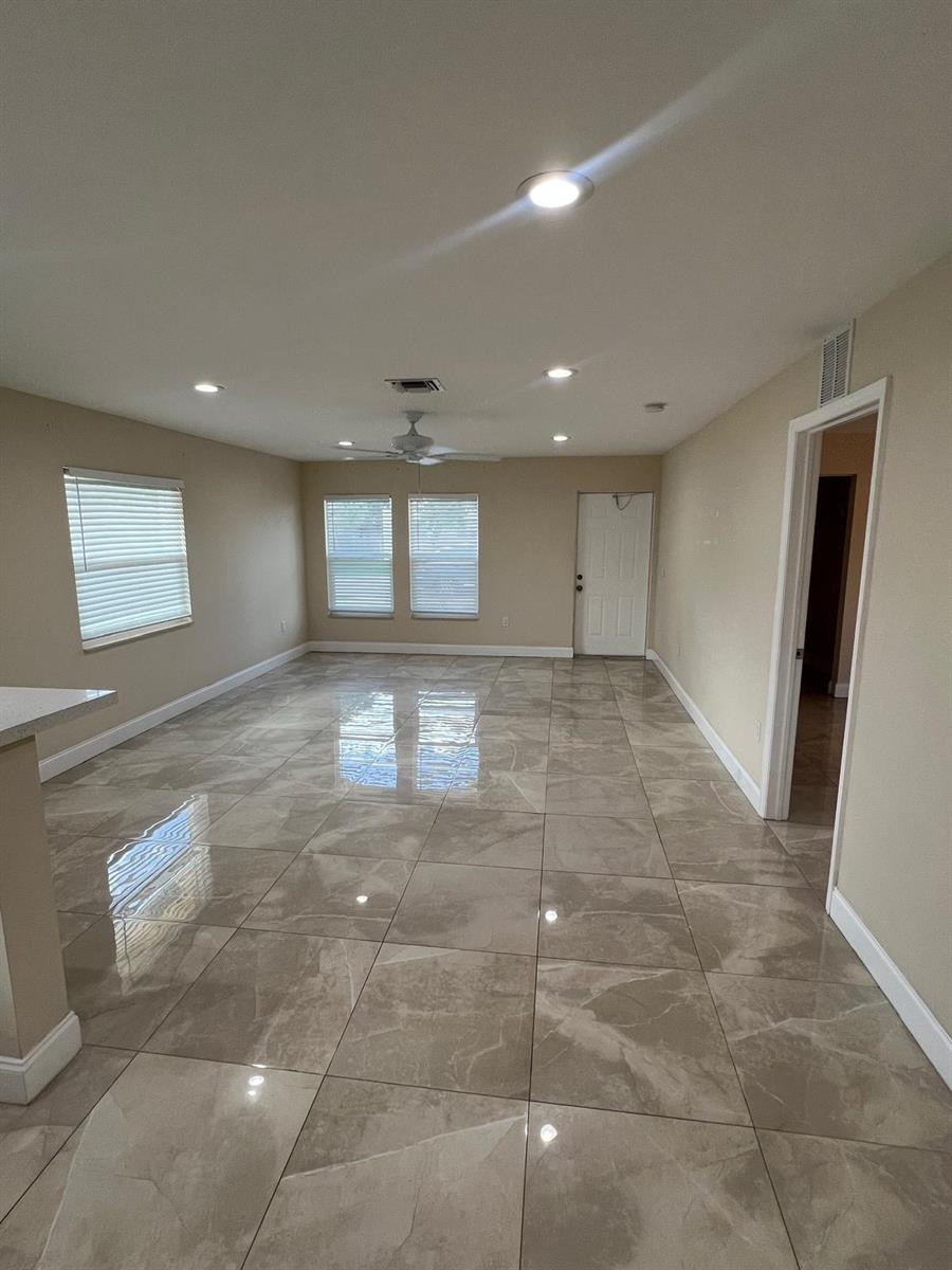 An empty room features large, glossy, light-brown marble-look floor tiles and recessed ceiling lighting — 962 29th Street, West Palm Beach FL 33407, WEST PALM BEACH, FL