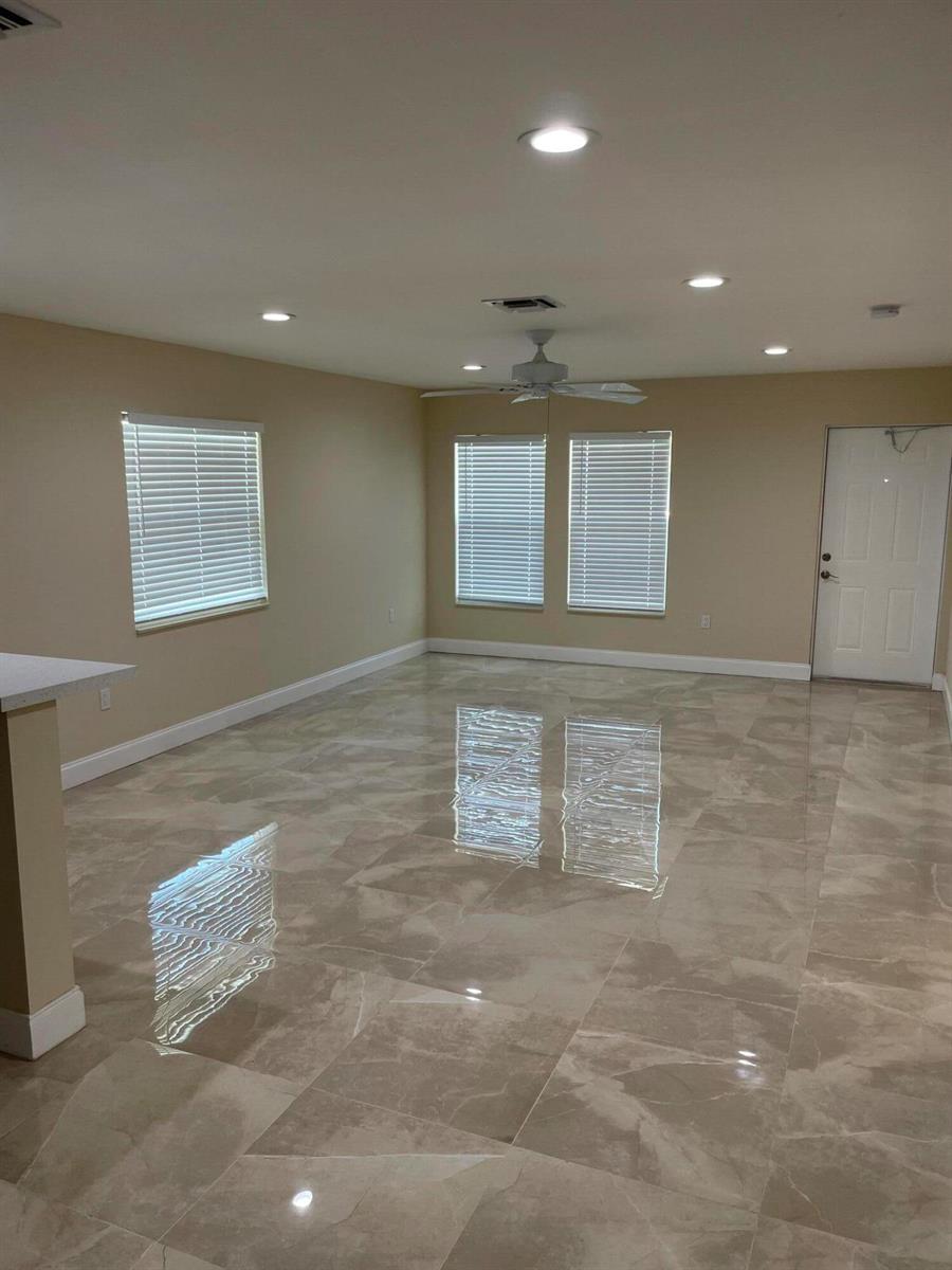 An empty room with beige walls, large glossy floor tiles, and a ceiling fan — 962 29th Street, West Palm Beach FL 33407, WEST PALM BEACH, FL