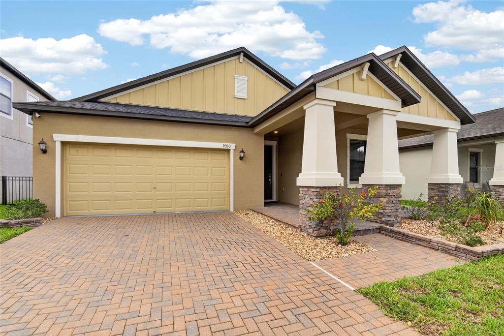 A single-story house with a tan stucco exterior, a brick paver driveway, and a covered porch — 9930 IVORY DRIVE, RUSKIN, FL