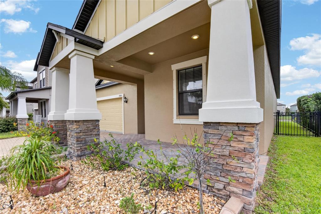 A covered entryway with stone-based pillars leads to a garage and a front window — 9930 IVORY DRIVE, RUSKIN, FL