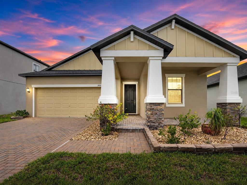 A single-story house exterior features a paved driveway, stone-accented columns, and a covered entryway — 9930 IVORY DRIVE, RUSKIN, FL