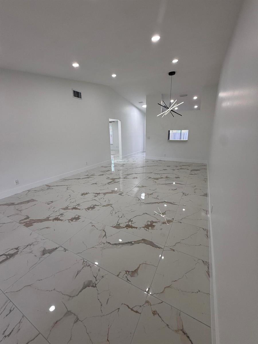 A bright, empty room features large white marble-patterned floor tiles and a modern sputnik chandelier — 817 Sky Pine Way # H, FL 33415, FL