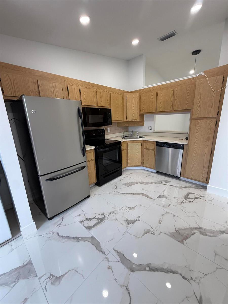 A kitchen features oak cabinets, stainless steel appliances, and white marble-patterned tile flooring — 817 Sky Pine Way # H, FL 33415, FL
