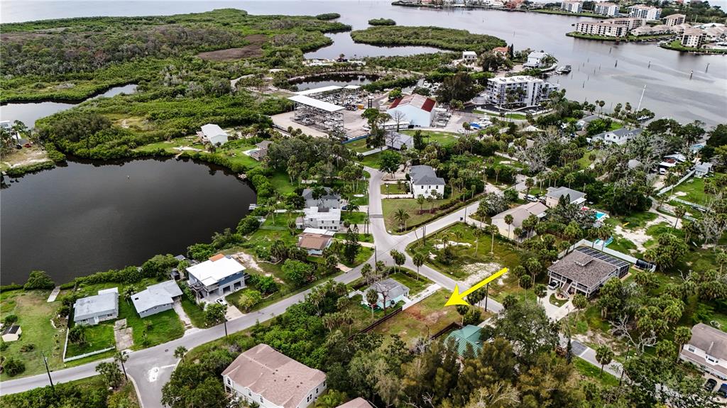 An aerial view shows a vacant residential lot marked by a yellow arrow near water — 4846 LIMESTONE DRIVE, PORT RICHEY, FL