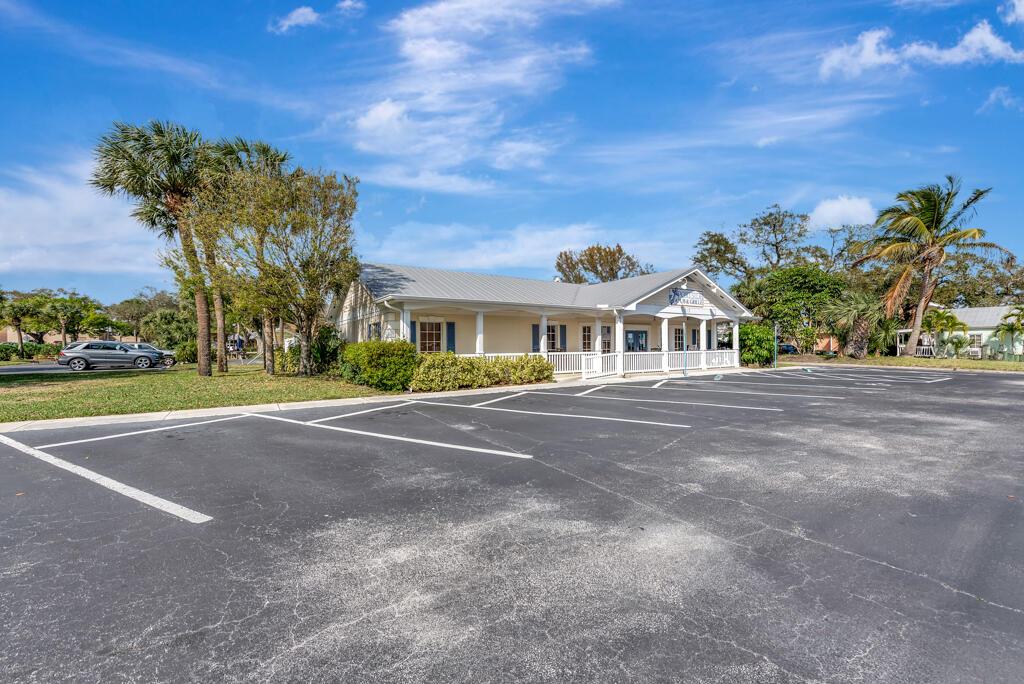A single-story commercial building with a covered porch sits behind a large asphalt parking lot — SEBASTIAN, FL