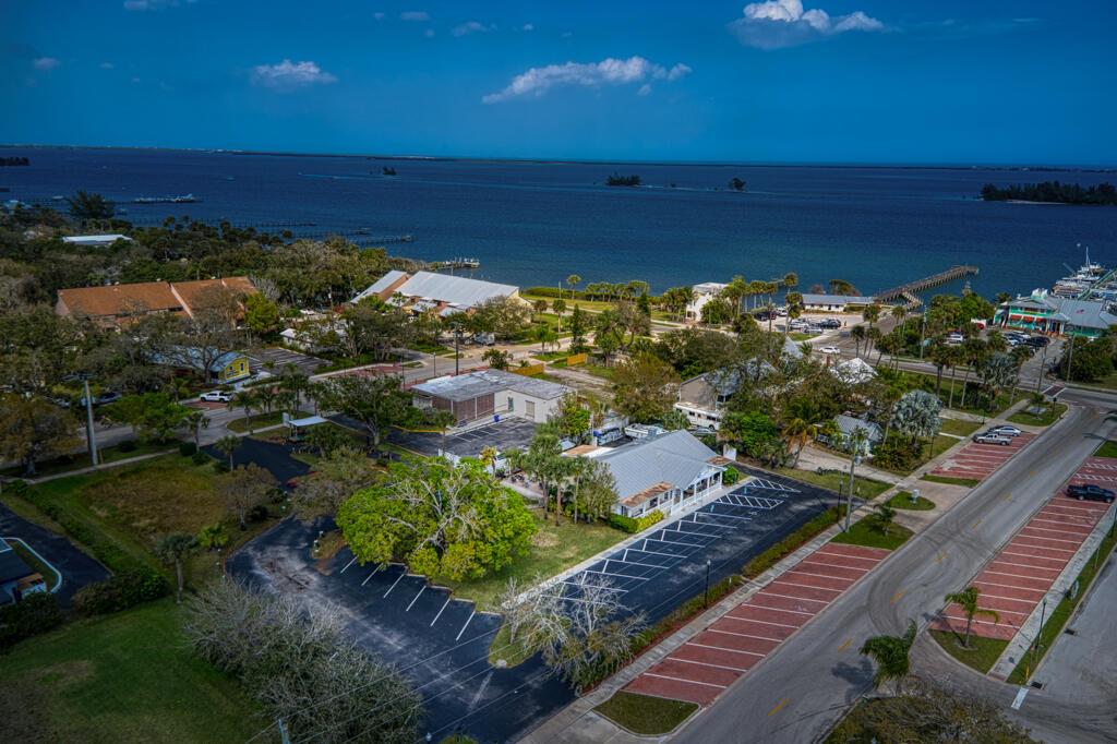 An aerial view shows a coastal property with a parking lot, buildings, and nearby water — SEBASTIAN, FL