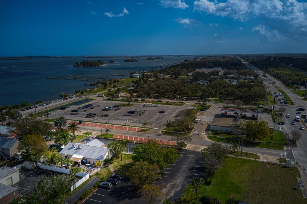 An aerial view shows a parking lot, a waterfront park, and a nearby road — SEBASTIAN, FL