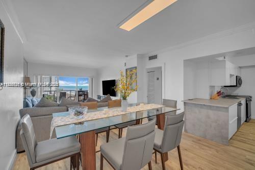 A dining area with a glass table and gray chairs opens to a living room view — 1950 S Ocean Dr # 6K, Hallandale Beach FL 33009, HALLANDALE BEACH, FL
