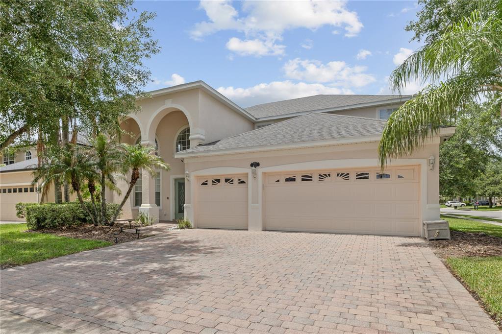 A two-story house with a beige stucco exterior, a three-car garage, and a paver driveway — 212 KAYS LANDING DRIVE, SANFORD, FL