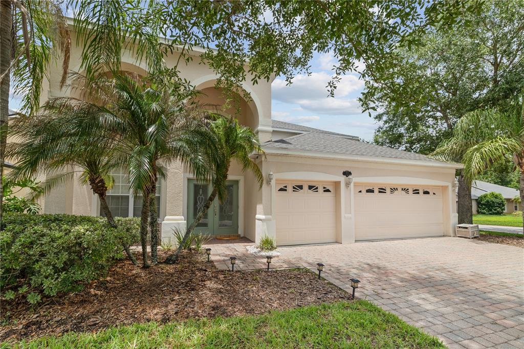 A two-story house with a beige stucco exterior, a three-car garage, and a paved driveway — 212 KAYS LANDING DRIVE, SANFORD, FL