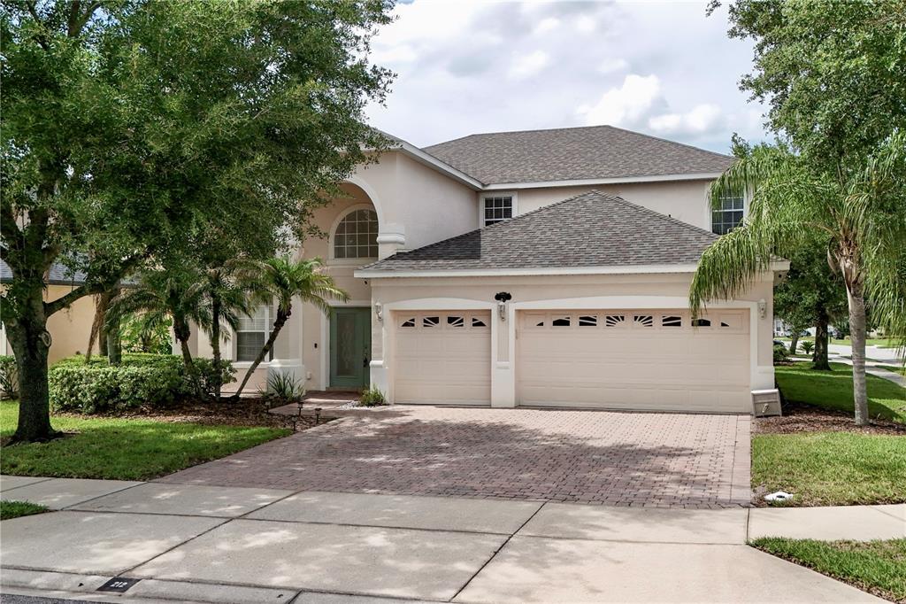 A two-story house with a three-car garage and a paved driveway under a cloudy sky — 212 KAYS LANDING DRIVE, SANFORD, FL