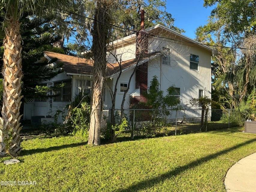A two-story house with a brick chimney and a chain-link fence in the yard — 711 S PALMETTO AVENUE, DAYTONA BEACH, FL
