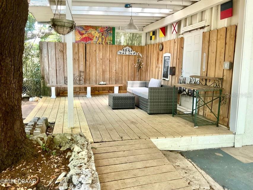 A covered wooden deck features a seating area, a bench, and a metal table — 711 S PALMETTO AVENUE, DAYTONA BEACH, FL