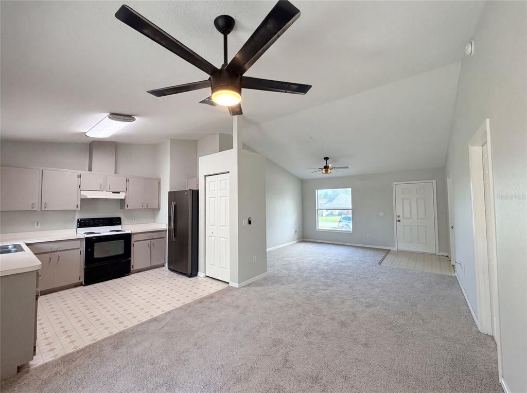 An open-concept kitchen with gray cabinets and a carpeted living area with a ceiling fan — 17956 SW 25TH AVENUE ROAD, OCALA, FL