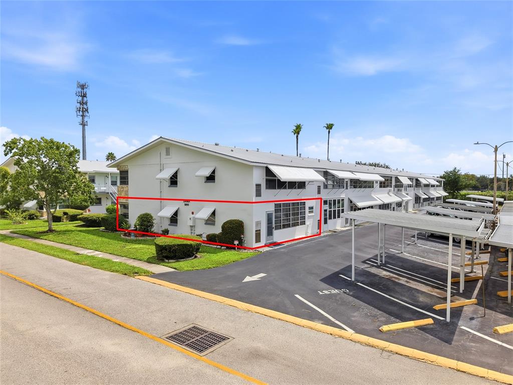 A two-story apartment building exterior features white walls, awnings, and a red-outlined ground floor unit — 5895 18TH STREET N UNIT 1, ST PETERSBURG, FL