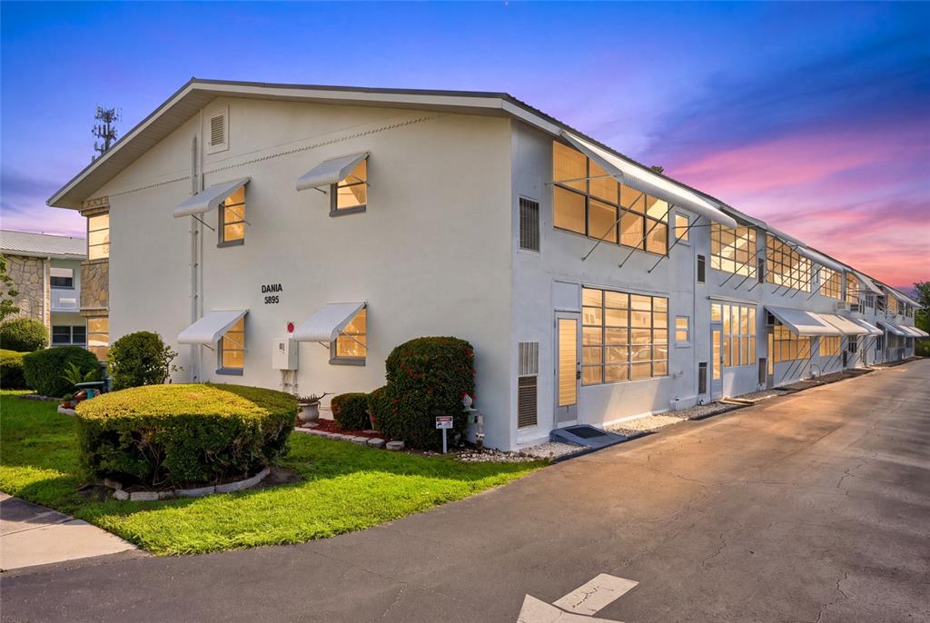 A two-story apartment building with white stucco walls and metal awnings over the windows — 5895 18TH STREET N UNIT 1, ST PETERSBURG, FL