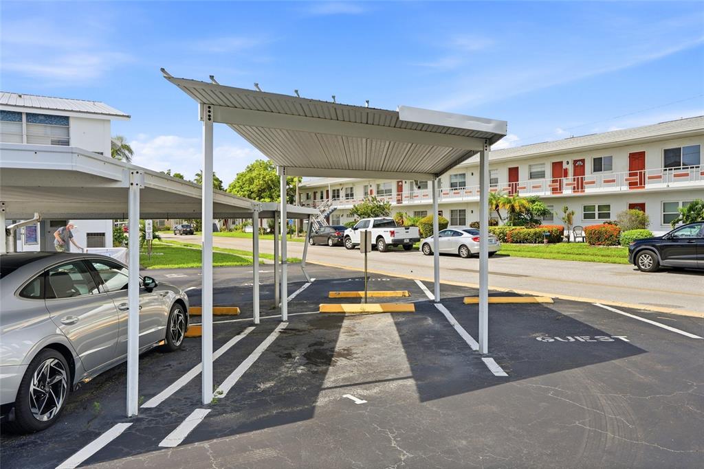 A parking lot with covered carports and apartment buildings in the background — 5895 18TH STREET N UNIT 1, ST PETERSBURG, FL