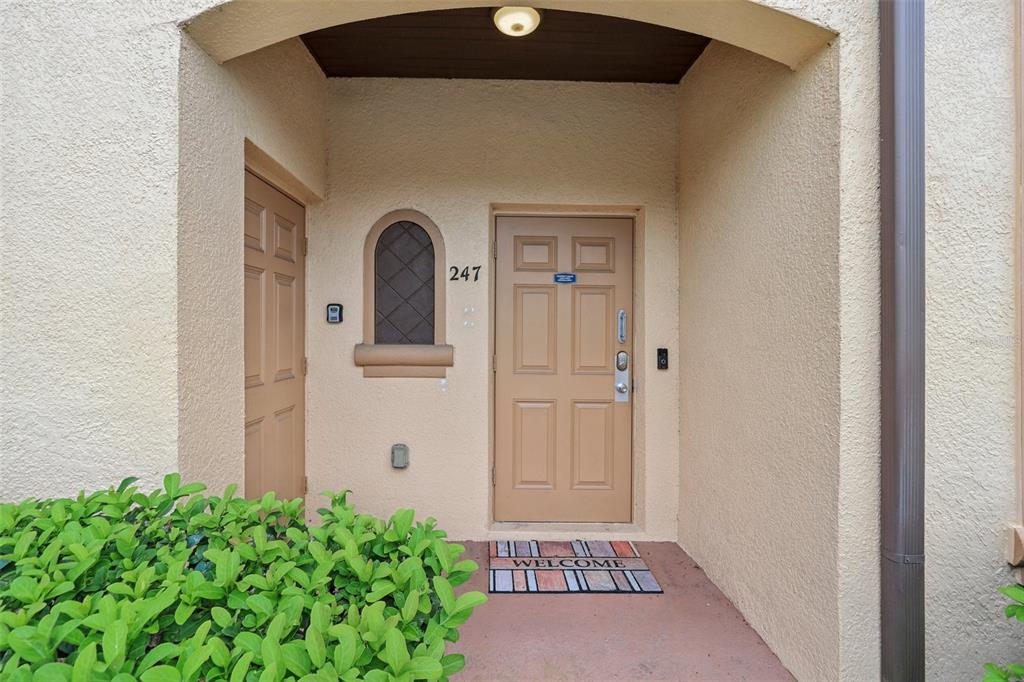 A tan stucco entryway features a front door, a small arched window, and a doormat — 247 CALABRIA AVENUE, DAVENPORT, FL