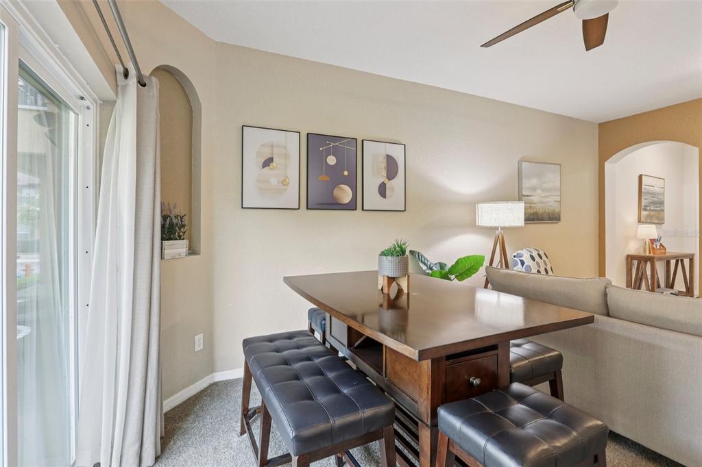 A dining area features a wooden table with tufted benches, wall art, and a sliding door — 247 CALABRIA AVENUE, DAVENPORT, FL