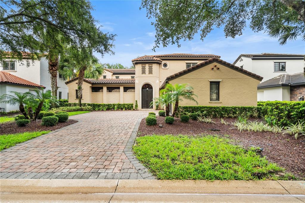 A tan stucco house with a brick paver driveway and a tiled roof — 9841 COVENT GARDEN DRIVE, ORLANDO, FL