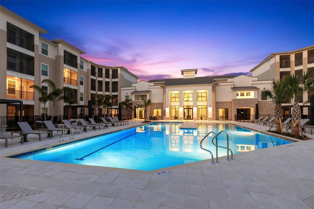 A swimming pool sits in the courtyard of a multi-story apartment building at dusk — 7210 INTERBAY BOULEVARD UNIT A3, TAMPA, FL