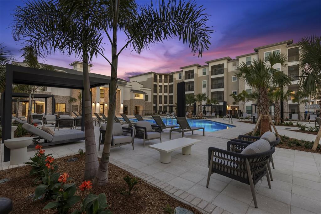 A swimming pool area with lounge chairs and palm trees at a multi-story apartment complex — 7210 INTERBAY BOULEVARD UNIT A3, TAMPA, FL